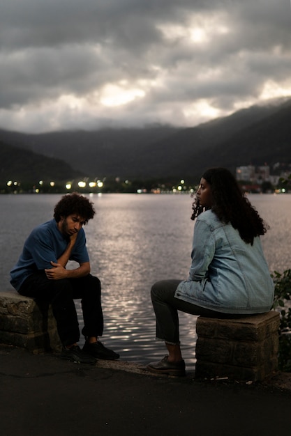 sad-couple-sitting-together-outdoors_23-2150516260